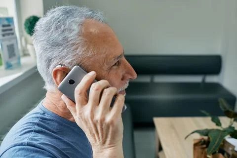 Using your hearing aids with a smartphone . Senior man with hearing aid behin Foto stock