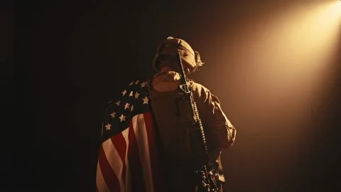 USMC soldier standing with his back to us in the dark holding USA national flag Stock Footage 155689967