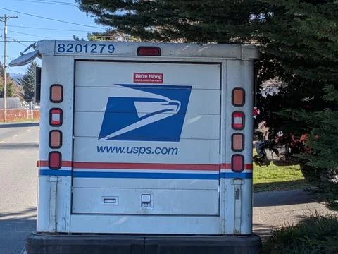 USPS mail vehicle with eagle logo and “We Are Hiring” sign parked Foto stock