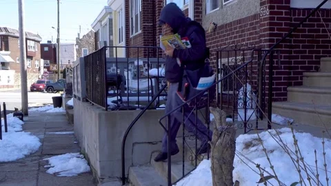 A USPS worker delivers mail in North Philadelphia on a cold day in March. Vídeos de archivo 138830257