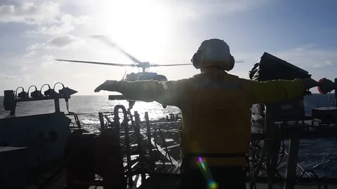 USS Curtis Wilbur flight deck crew signalling to MH-60 Seahawk helicopter pilot Stock Footage 104855698