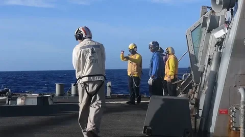 USS Curtis Wilbur flight deck crew signalling to helicopter pilot Stock Footage 104855796