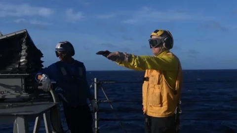 USS Curtis Wilbur flight deck crew signalling to helicopter pilot Stock Footage 104855797