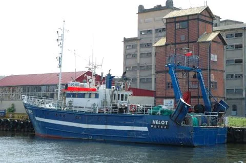 Ustka, Poland - May 24, 2014: Fishing vessel and old factory buildings in har Stock Photos
