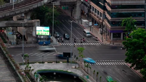 Usy intersection features cars driving under elevated train tracks 動画素材 286112904