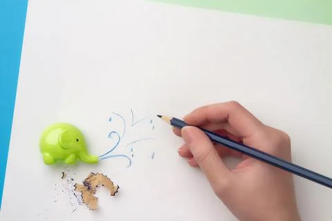 ?ute children's sharpener in the form of an elephant, hand with blue pencil d Stock Photos