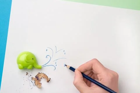 ?ute sharpener in the form of an elephant, hand with blue pencil drawing erup Stock Photos