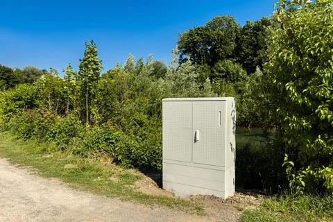 Utility box beside a path surrounded by lush greenery Stock Photos