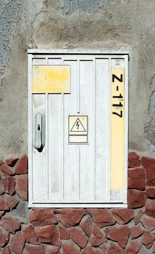 Utility box at the edge of a rustic building with stone wall showcasing signs Stock Photos