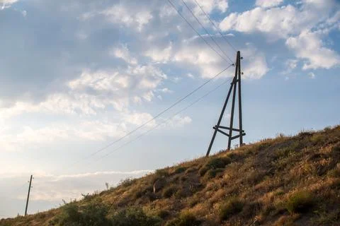 Utility infrastructure on rural hillside during daytime with scattered clouds Stock Photos