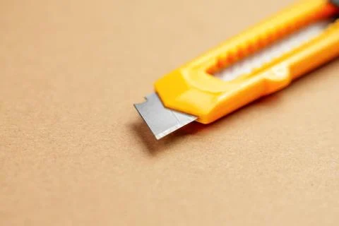 Utility knife or retractable box cutter for parcel unpacking on a brown kraft 库存照片