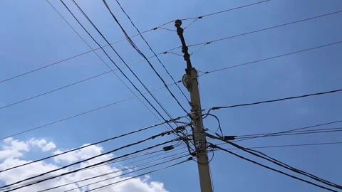 Utility pole with dense overhead power cables against blue sky in urban daylight Stock Footage 337937427