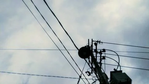 A utility pole with electrical wires stands against a cloudy sky, showcasing  Stock Photos