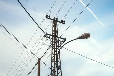 Utility pole with intersecting power lines and a curved streetlight set aga.. Stock Photos