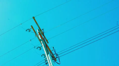 Utility pole with power lines against clear blue sky 動画素材 337619720