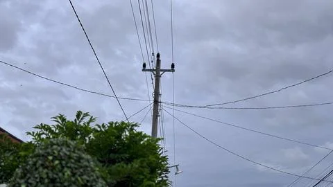 Utility Pole with Power Lines Under Cloudy Sky Stock Photos