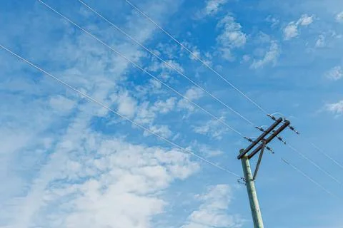 Utility pole with power lines under blue sky and clouds Stock Photos