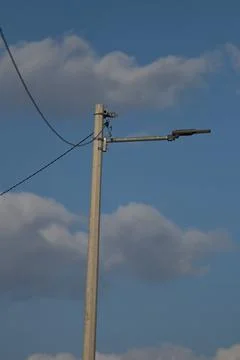 Utility pole with streetlight against a backdrop of blue sky and clouds dur.. Stock Photos