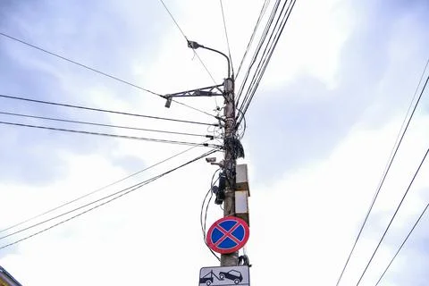 Utility pole with tangled overhead power and communication lines against a Stock Photos