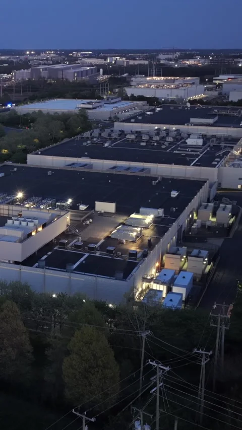Utility poles and power lines cross the foreground as a data center campus Stock Footage 345728366