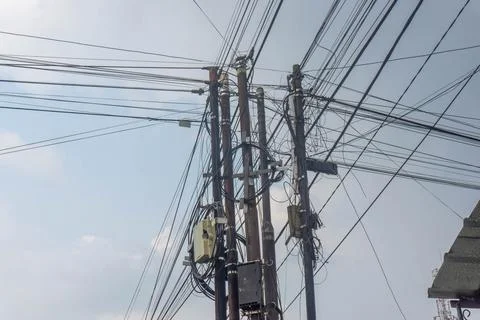 Utility poles with multiple cables intersect, forming a complex network Stock-Fotos