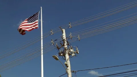 Utility Poll With Power Lines Next To An American Flag Blowing In The Wind  库存影片 76901846