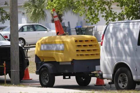 Utility van with yellow compressor trailer with jackhammer machine on road Stock Photos