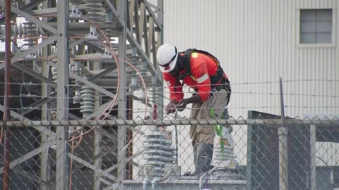 Utility Worker Adjusting Equipment At Fenced Substation Stock Footage 331057813