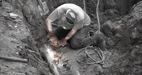 A utility worker eliminates an accident on a pipeline by electric welding Stock Footage 246934468