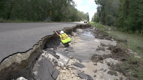 Utility worker inspects washed out road Stock Footage 96164000