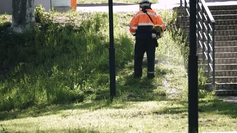 A utility worker mows the grass with a lawn mower Stock Footage 310872959