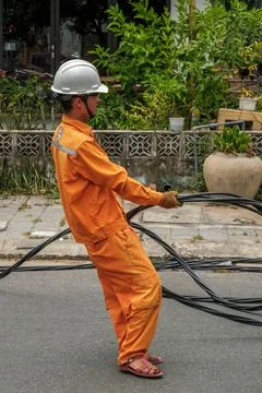 Utility Worker in Orange Uniform Pulling Heavy Black Electrical Cables Fotos Stock