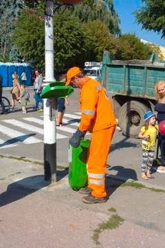 The utility worker removes garbage from the full tank. Day of the city. Zhito Stock Photos
