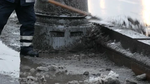 Utility worker removes melted snow and deicing agent from snowy sidewalk Stock Footage 138608548