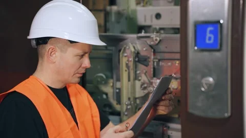 A utility worker repairs an elevator in a residential complex. A repairman in Video stock 265480507