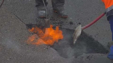 Utility Workers Fixing Gap in a Road by FIlling it with Hot Asphalt 스톡 사진