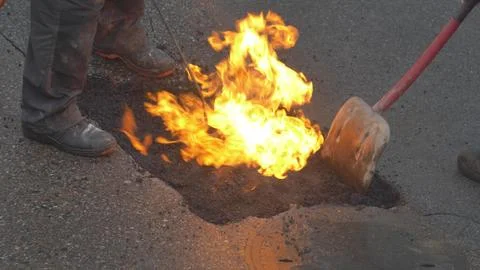 Utility Workers Fixing Gap in a Road by FIlling it with Hot Asphalt 스톡 사진