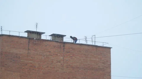 Utility workers remove snow from the roof of multi-storey building Vidéo 144998628