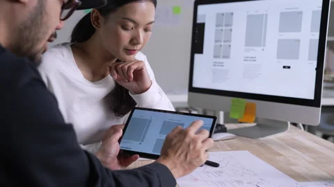 UX UI designer testing prototype on a tablet, discussing and brainstorming Stock Footage 291552022