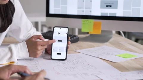 UX UI designer testing prototype on a phone, discussing and brainstorming Stock Footage 291552301