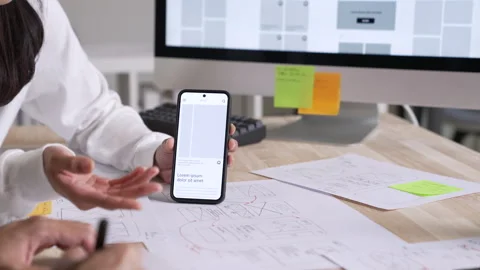 UX UI designer testing prototype on a phone, discussing and brainstorming Stock Footage 291552546
