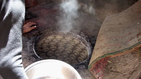 Uyghur man splashes water onto bread rolls inside traditional baking oven  스톡 동영상 129460118