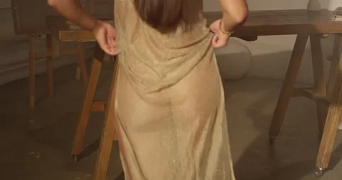 V1-0186 Beautiful brunette model in a gold dress plays with a camera. Attrac Stock Footage 165023341