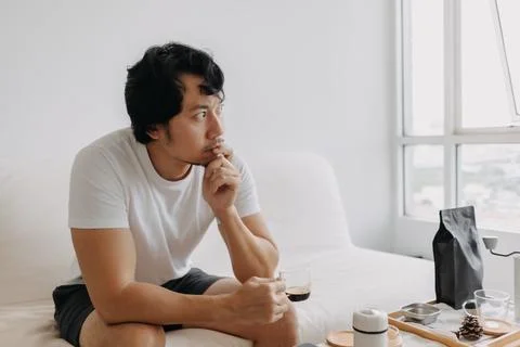 Vacant absent minded man staring out the windows, holding a coffee cup. Stock Photos
