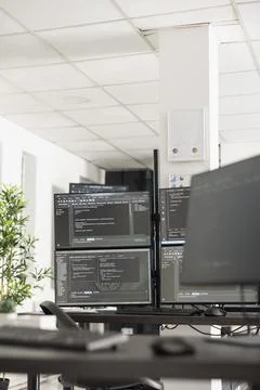 Vacant tech workspace with desktop monitors displaying coding scripts Stockfoto's