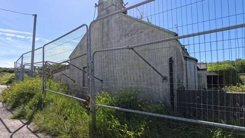 Vacant Welsh seafront cottage surrounded by security wired fencing and Video stock 339088874