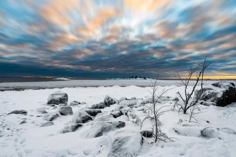 A vacation cloudscape of dramatic evening sky and snow covered half frozen la Stock Photos
