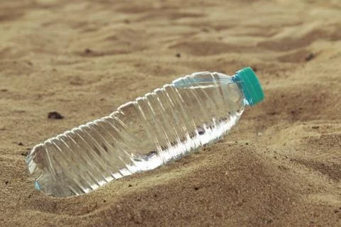 Vacation concept. Plastic bottle of drinking water on the sand of the sea beach Stock Photos