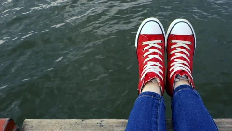 Vacation concept. At the right Person feet, red sneackers hang out, hanging over Video stock 154395553