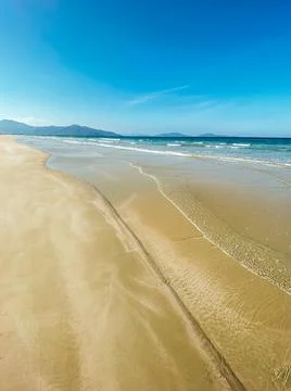 Vacation concept. Soft long waves tropical shore of a long empty sea beach Stock Photos